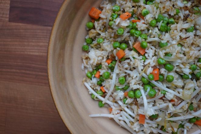 A plate of fried rice with peas, carrots, and other vegetables.