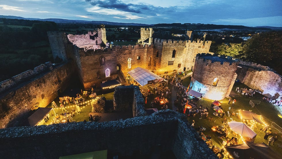 night festival in a lit medieval castle courtyard with tents and people