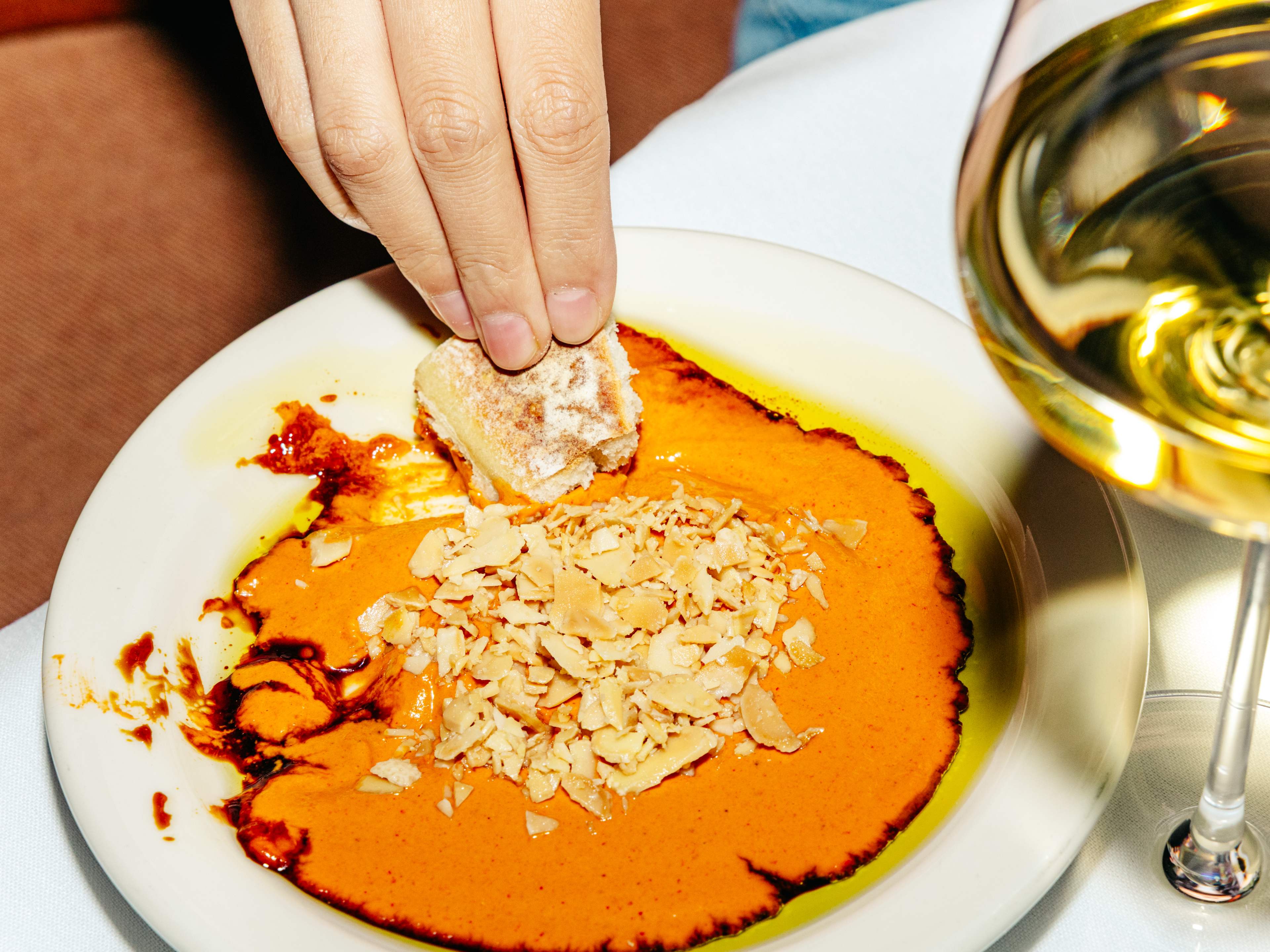 a hand dipping bread in dip at graciela