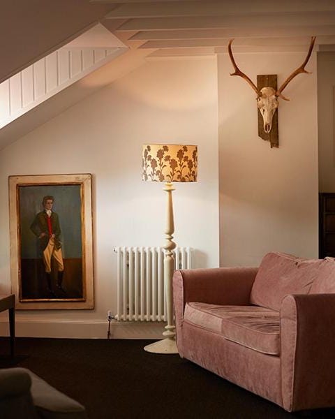 cozy attic room with a pink sofa, antler decor, and warm lighting.