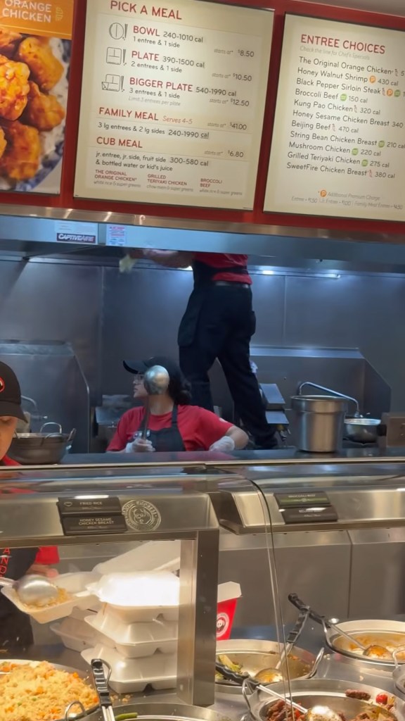 An employee steps on a frying station and sprays chemicals directly over food in a Panda Express.