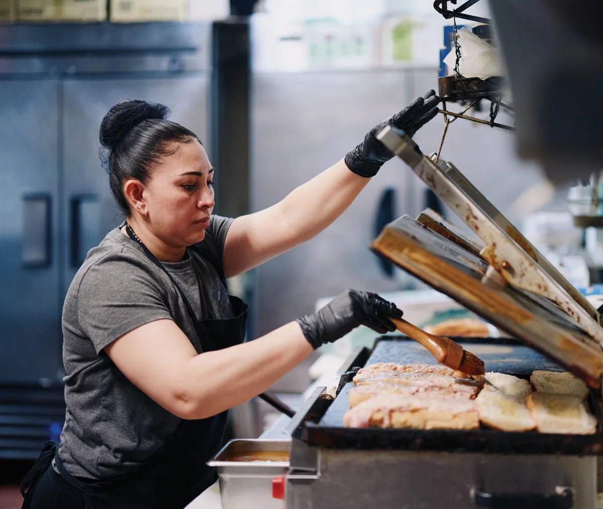 A cook prepares food at the sandwich press