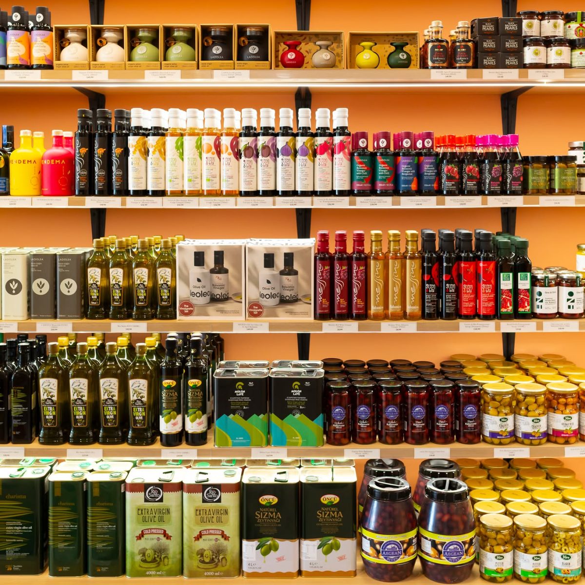 A pantry shelf stocked with many bottles of olive oil.