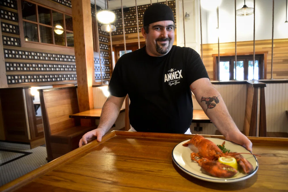 Team spirit: The head chef shows off a freshly boiled lobster and a tattoo to match.