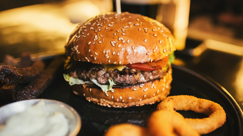 restaurant burger on black plate with onion rings and ranch
