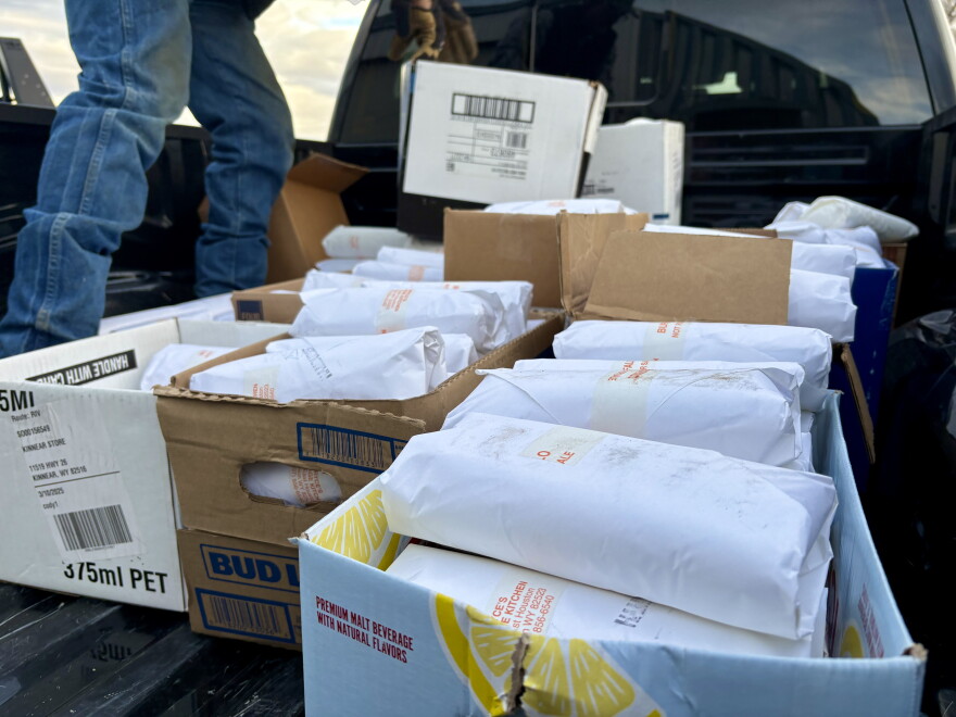 A close-up image of packages of bison meat, stacked in cardboard boxes in the back of a pickup truck.