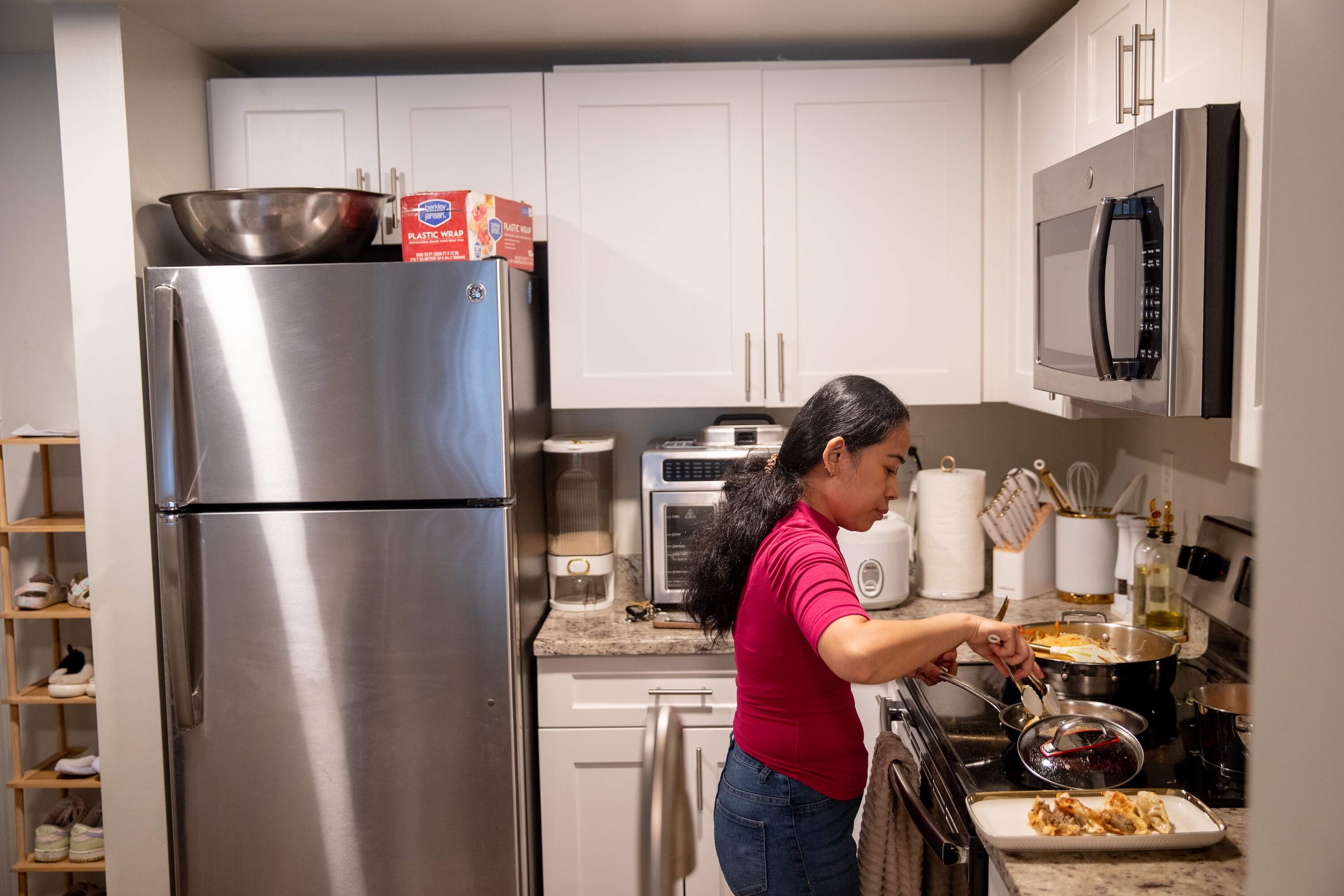 Janz Van prepares dinner for her daughter at her apartment kitchen in Malden. Van cooked and sold her made-to-order Ilocos empanadas from a previous apartment kitchen before she was forced to cease operations by the Malden Inspectional Services Department. Massachusetts doesn’t have a permitting process for perishable foods sold from residential kitchens. (Artemisia Luk/WBUR)