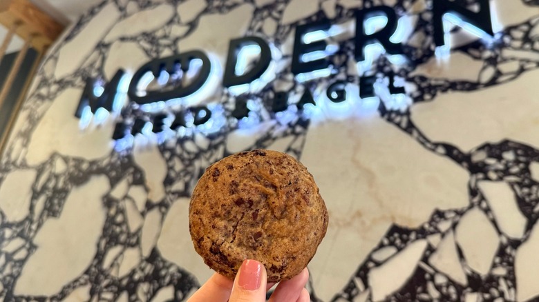 cooking behing held up against sign in Modern Bread and Bagel shop