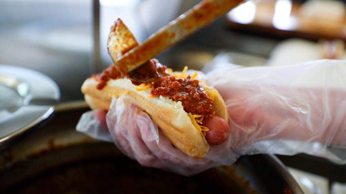 Chili is poured on top of a hotdog July 21, 2022, at Sam’s Hot Dog Stand in Lexington.