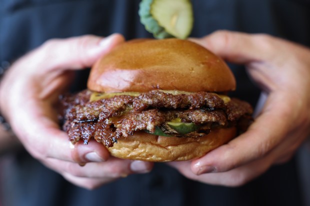 Operations manager Jay Goldberg holds a double smash cheeseburger at Chicago Culinary Kitchen barbecue restaurant and bar in Palatine on Sept. 23, 2026. Goldberg is a vocal critic of the proliferation of AI food imagery, menus and marketing on social media. (John J. Kim/Chicago Tribune)