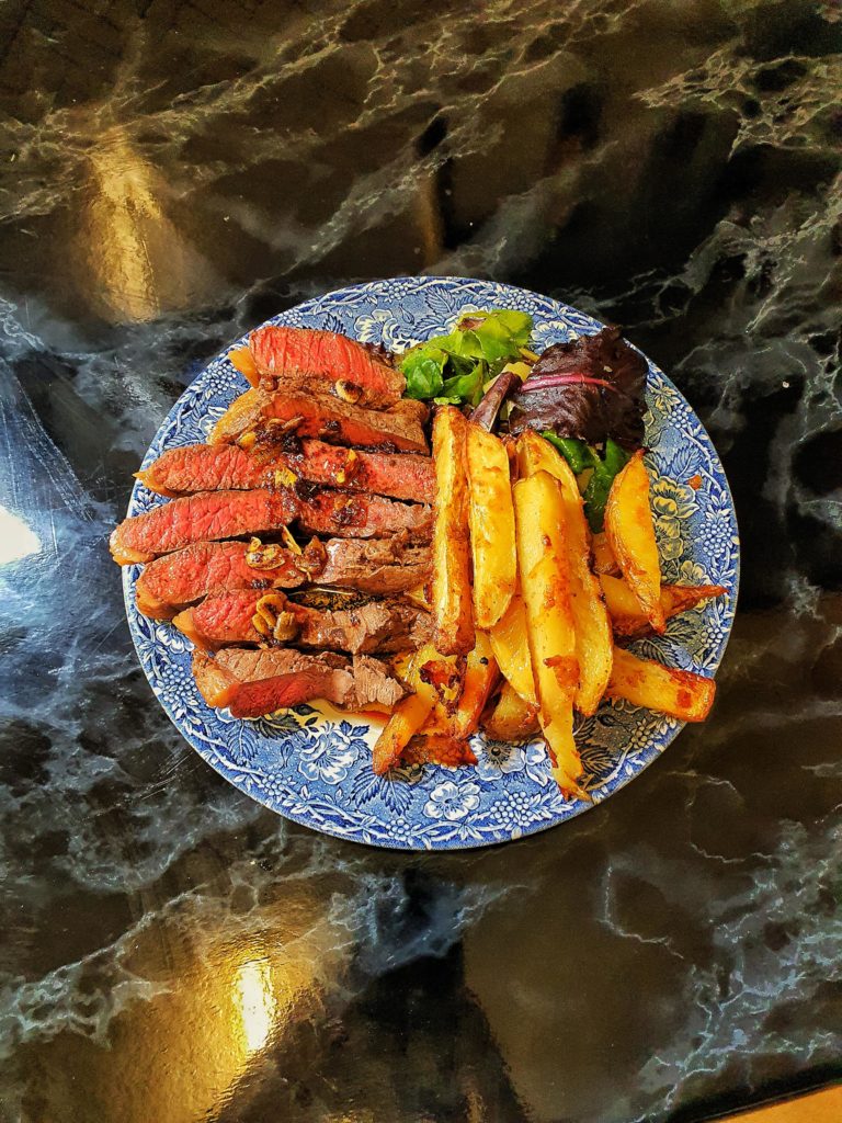 Medium rare Wagyu rump with crispy, crispy chips and a quick leafy salad with Parmesan. Garlic butter over the steak.