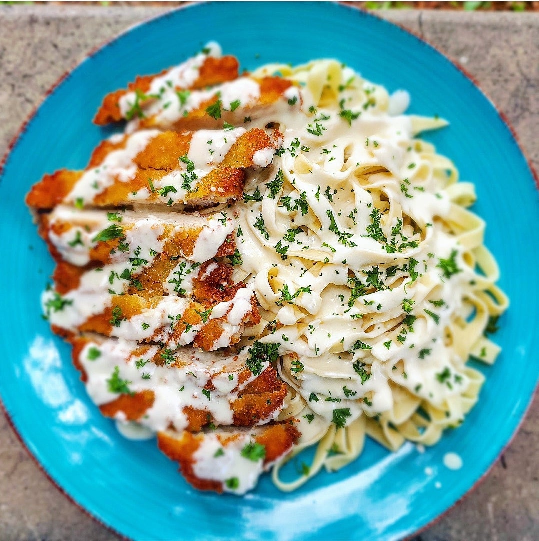 Homemade fettuccini alfredo pasta with panko breaded chicken thighs for