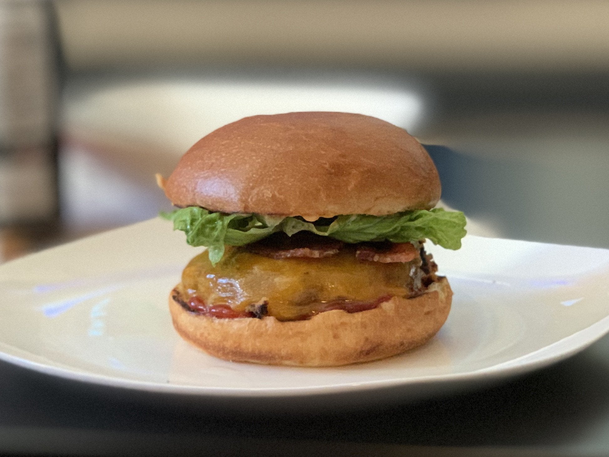 Homemade bacon cheddar burger with lettuce, ketchup, and chipotle mayo