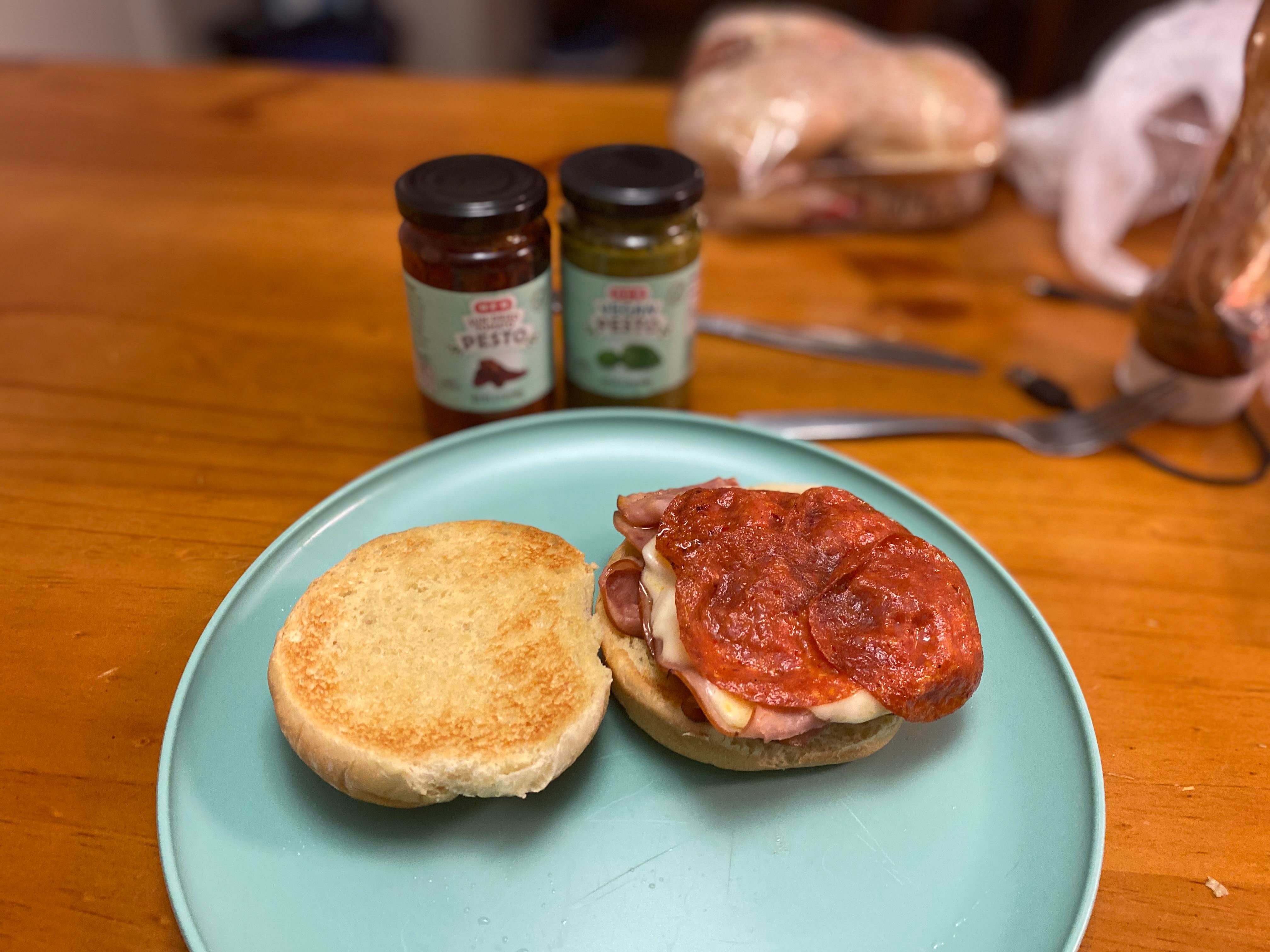 Ham sandwich with some pepperoni provolone cheese and pesto on the side