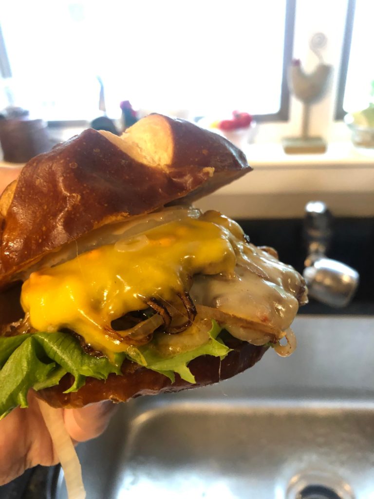 Double smash on pretzel bun with fried onions, raw onion lettuce pickles and burger sauce