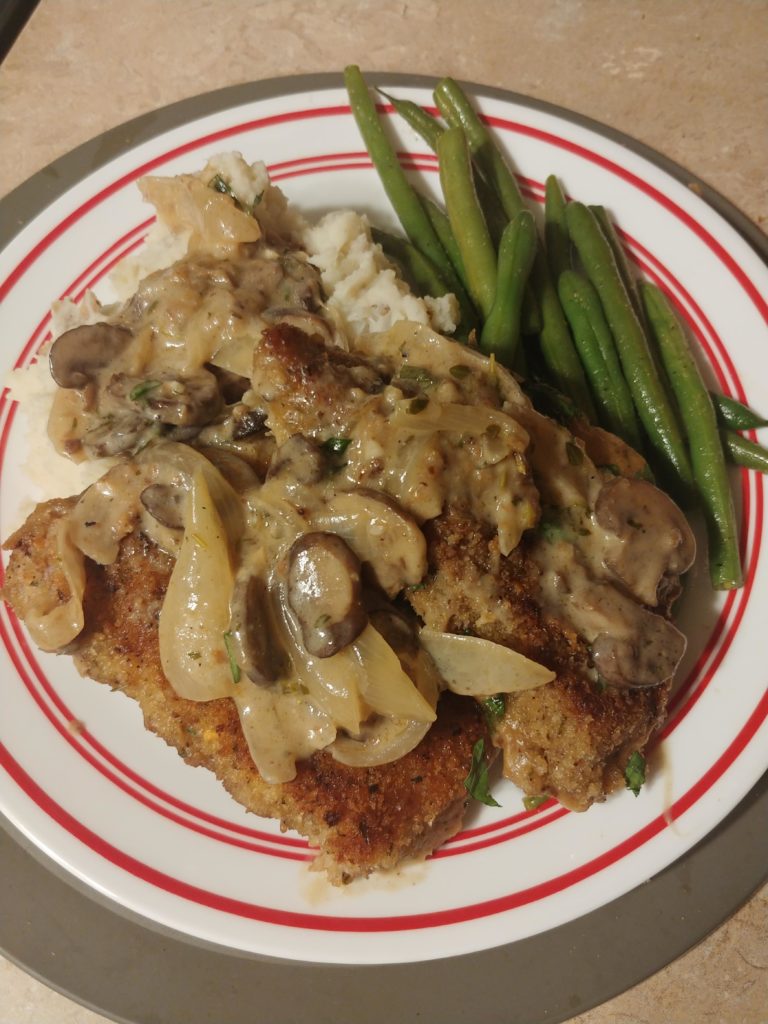 Breaded pork chops and roasted garlic mashed potatoes topped with mushroom gravy and green beans