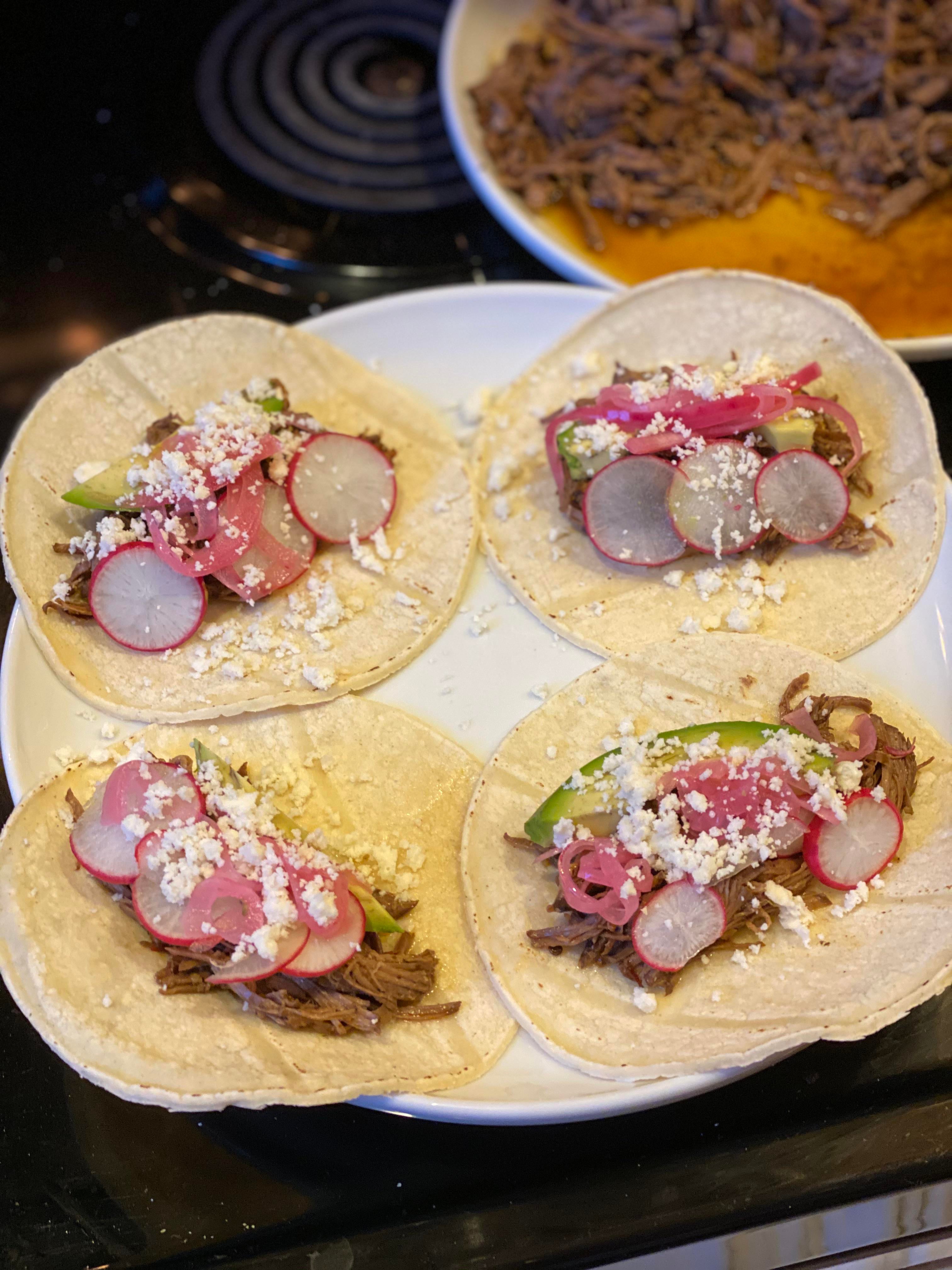 Barbacoa tacos with radish, avocado, pickled red onion and cotija for