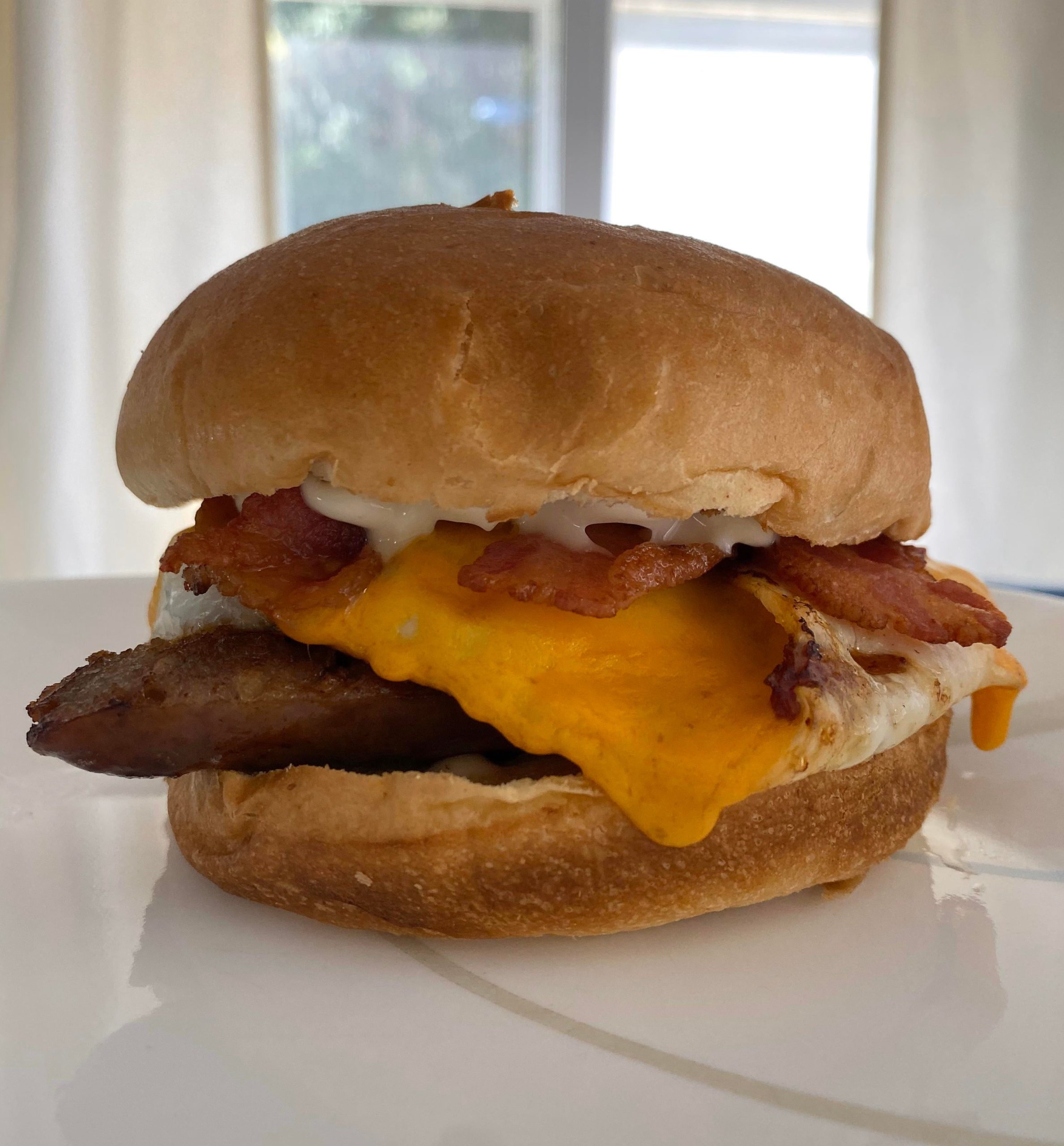Long weekend breakfast sandwich. Bacon, egg, cheddar and bratwurst on a