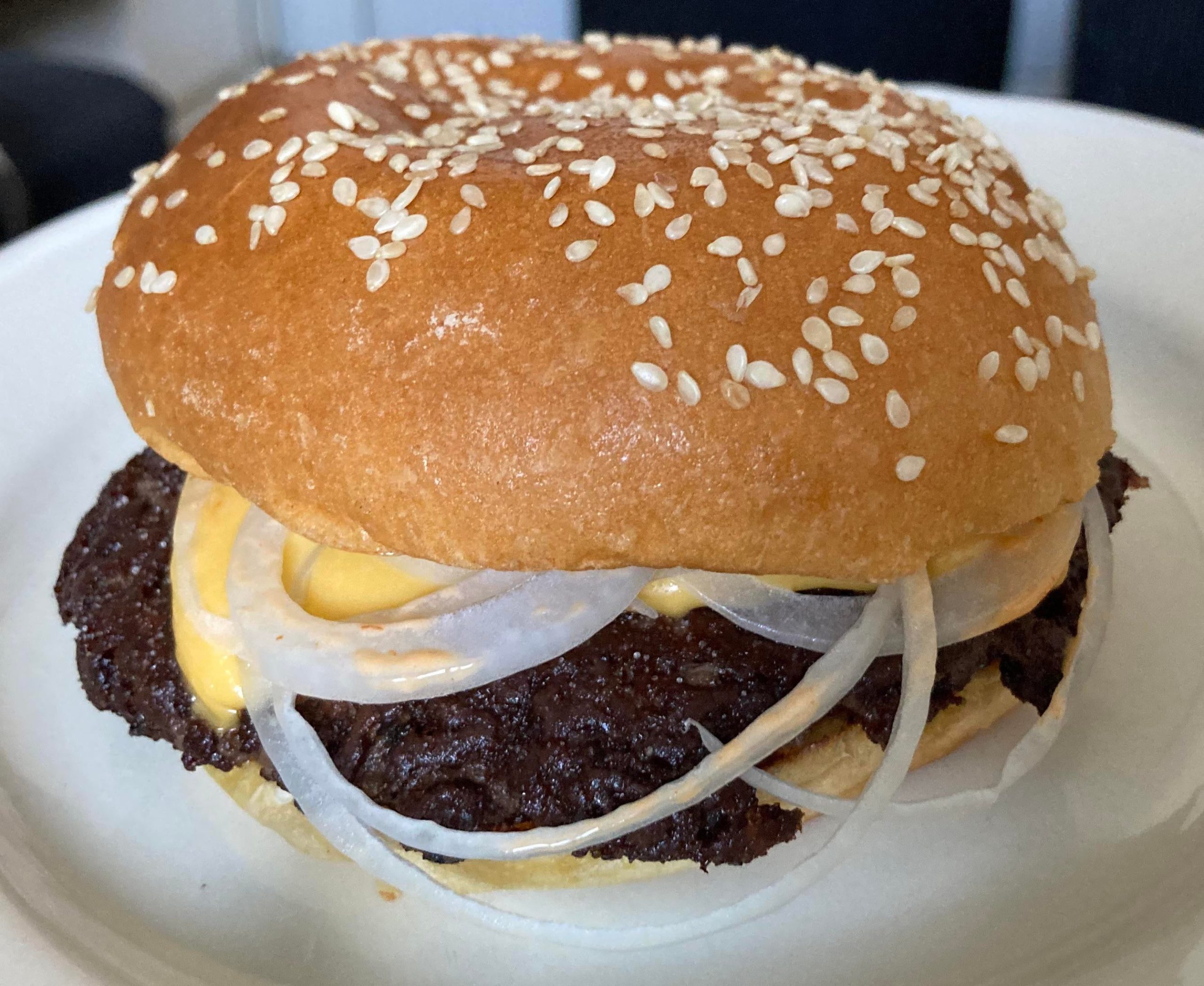 Cheeseburger with silverskin onions between a sesame brioche bun