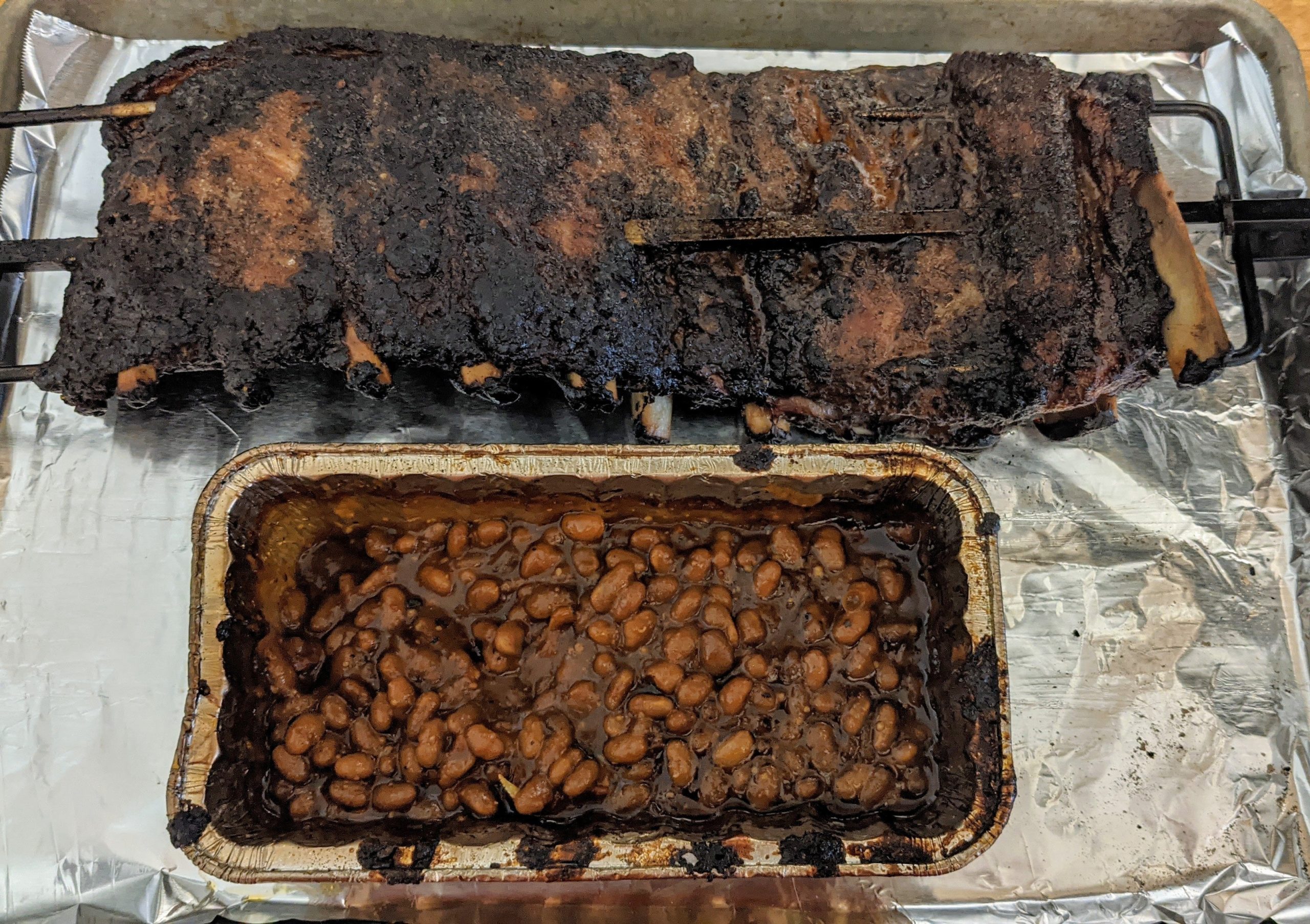 Rotisserie spare ribs over some beans, smoked with hickory on my er