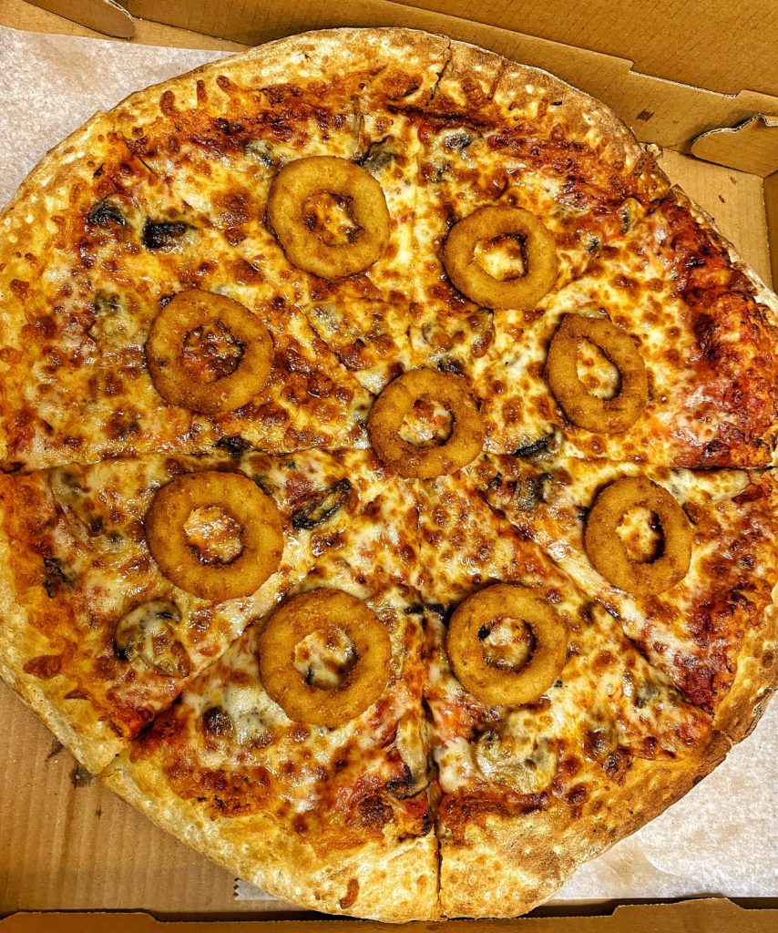 Birthday feast of onion rings atop mushroom pizza