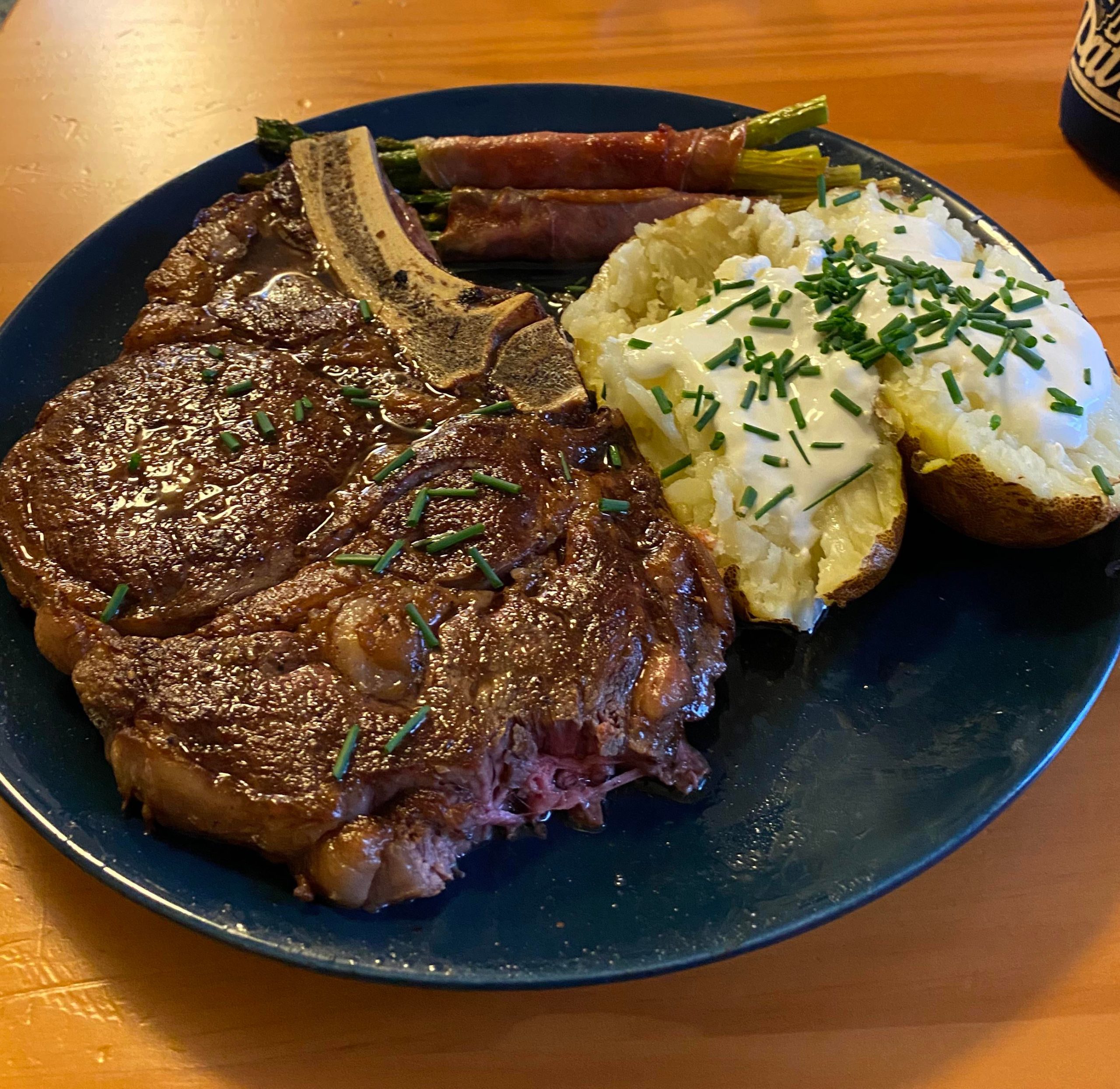 Cast iron bonein ribeye w/ baked potato and prosciutto wrapped