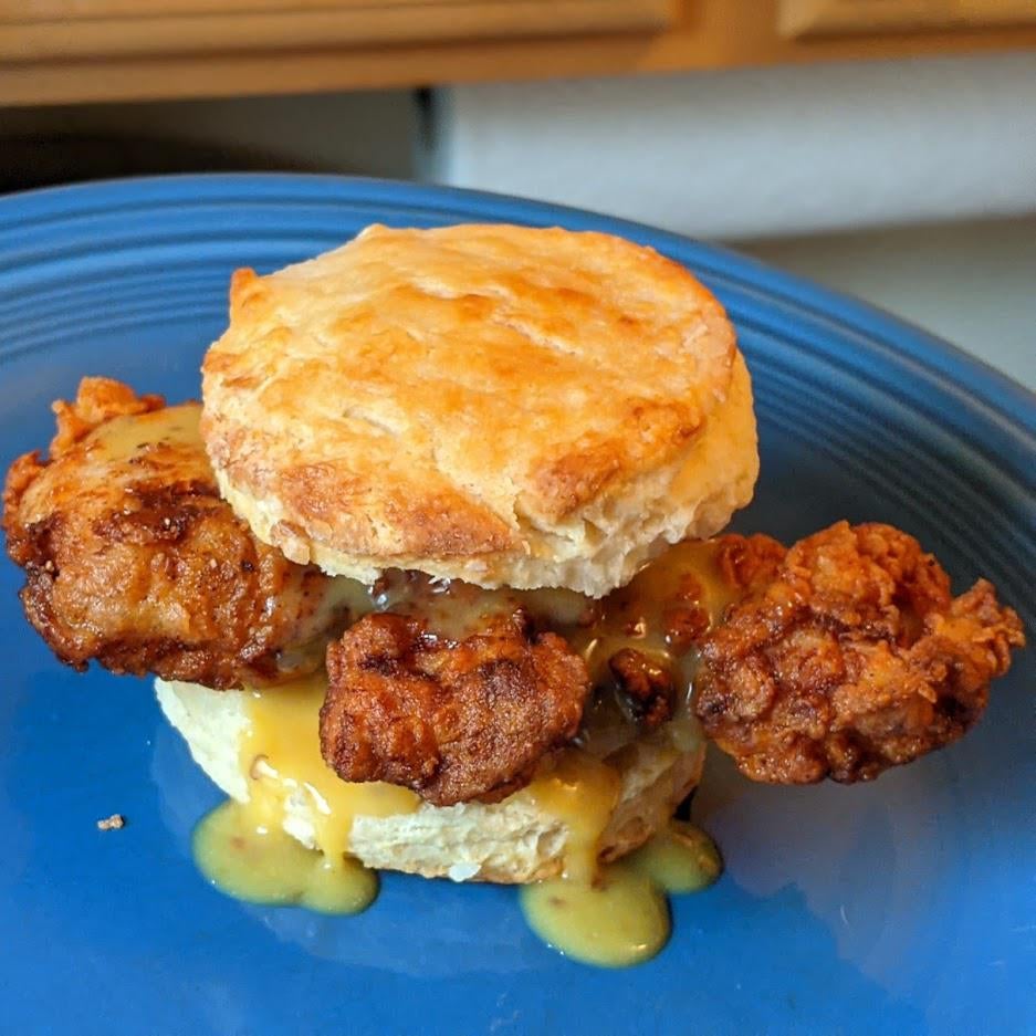 Buttermilk biscuit and fried chicken thigh with a little bit of honey mustard Dining and Cooking