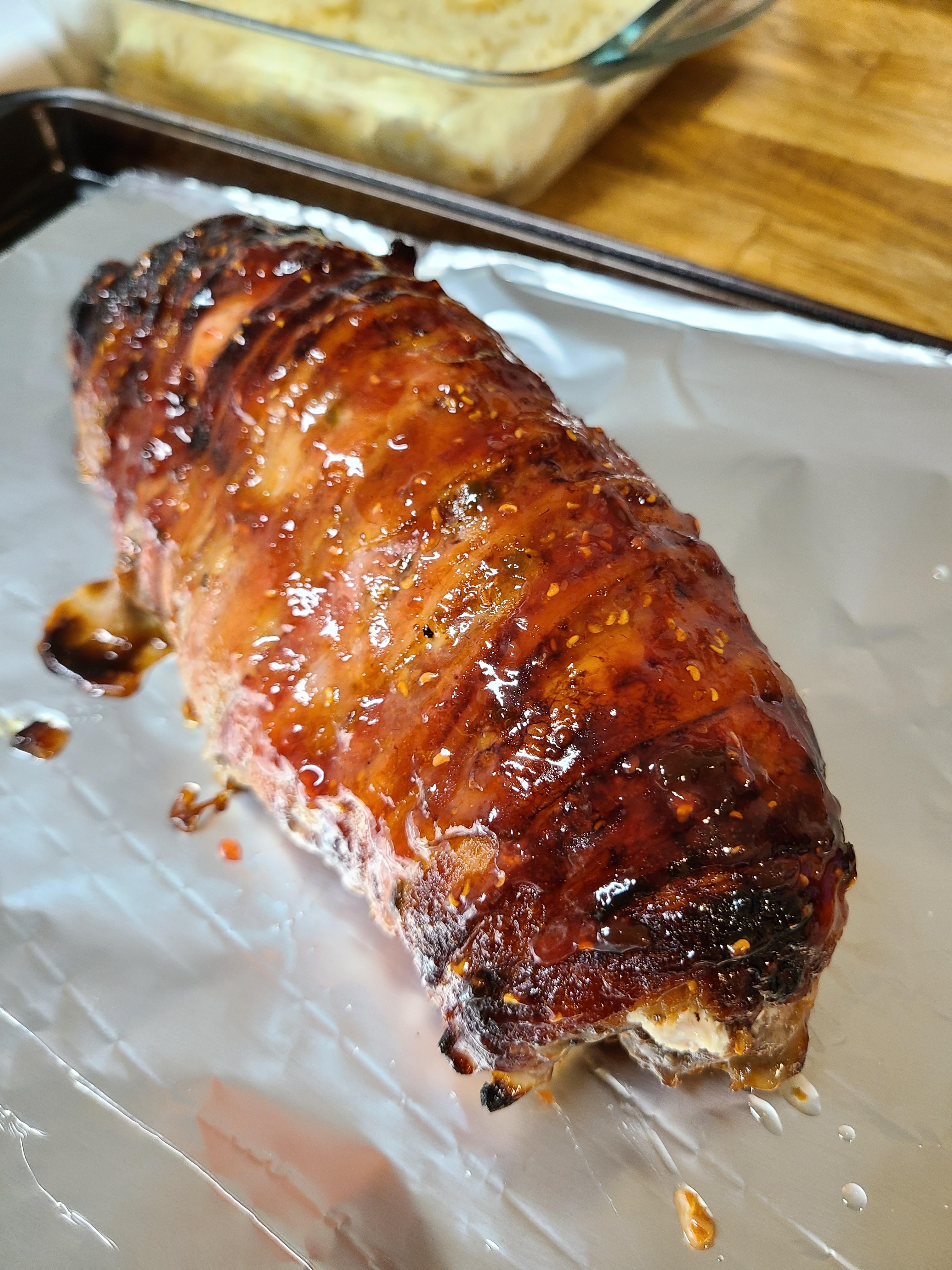 Cream cheese stuffed, bacon wrapped pork loin with a raspberry chipotle