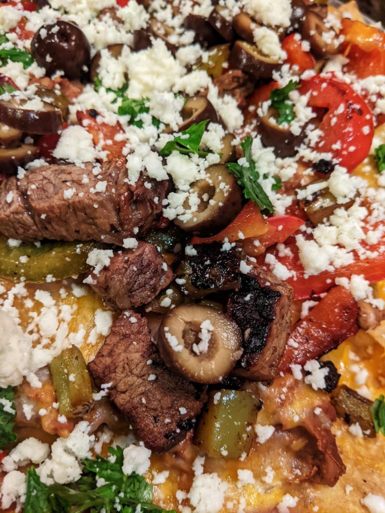Super Nachos with grilled tri-tip, refried beans, four Mexican cheese blend, fresh sliced red and green bell peppers, and sliced black olives. Topped with queso fresco and cilantro.