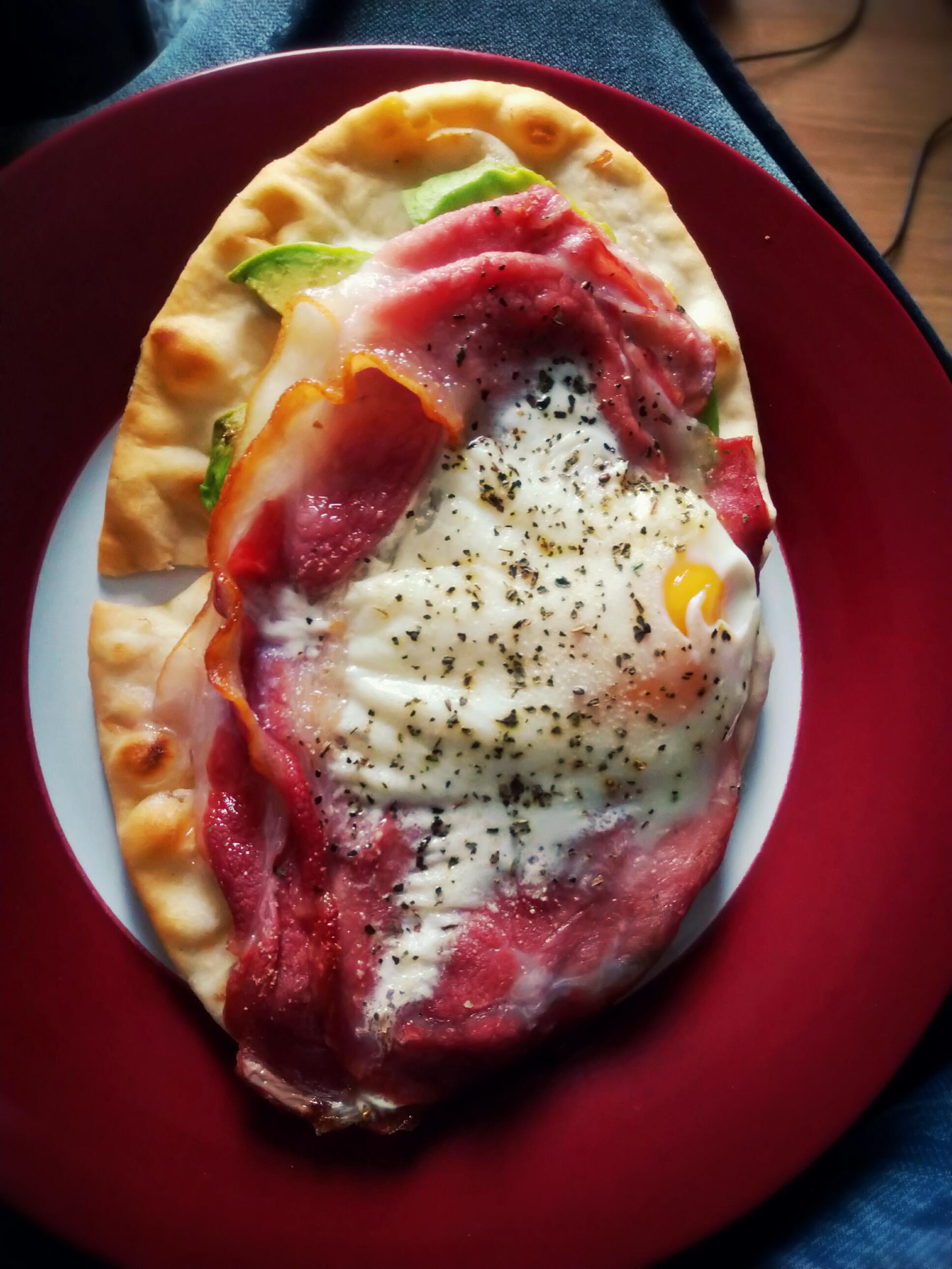Pita bread with avacado base, bacon and egg with garlic and basil on