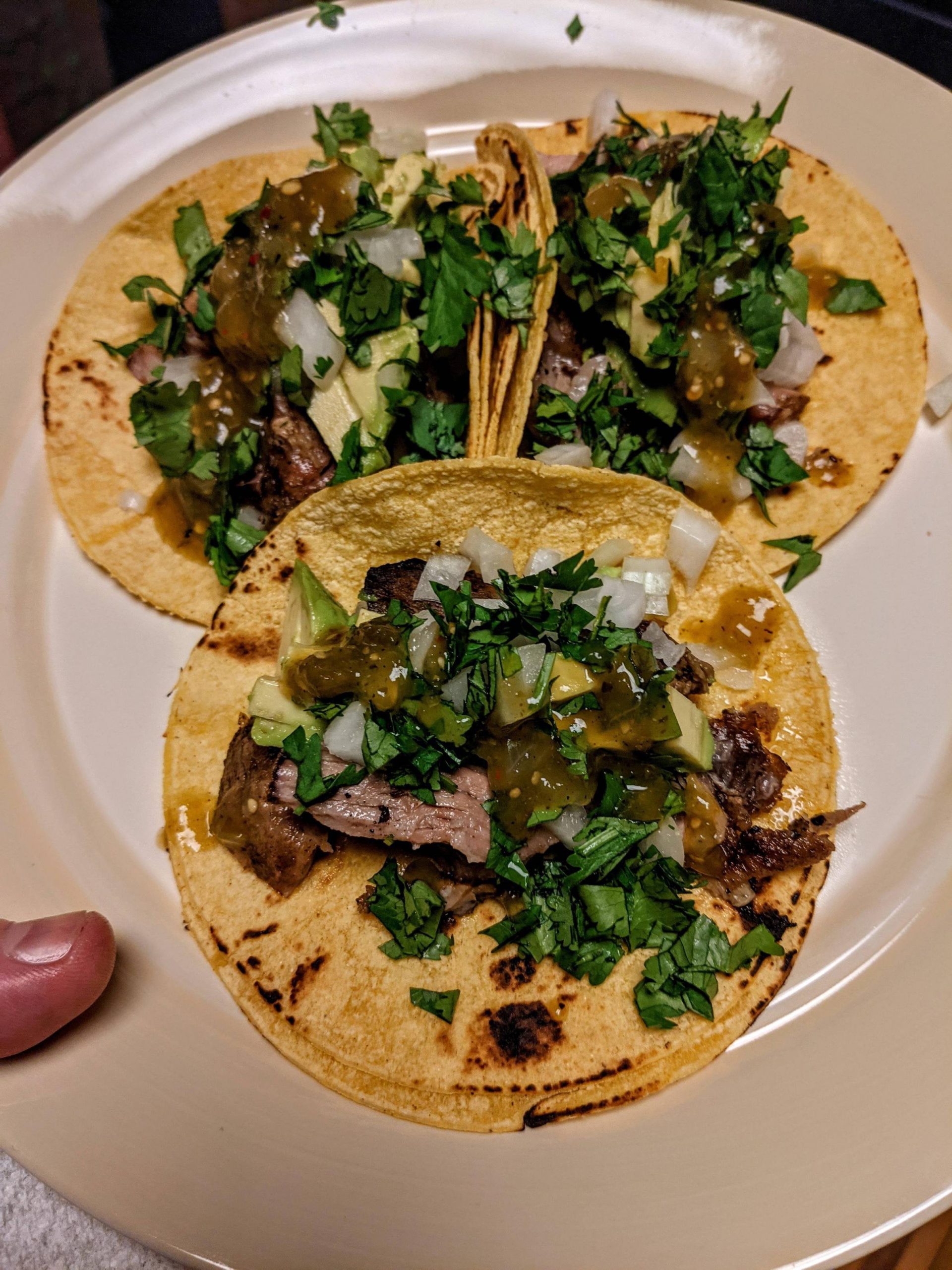 Crispy carnitas tacos with avocado, cilantro, onion and salsa verde