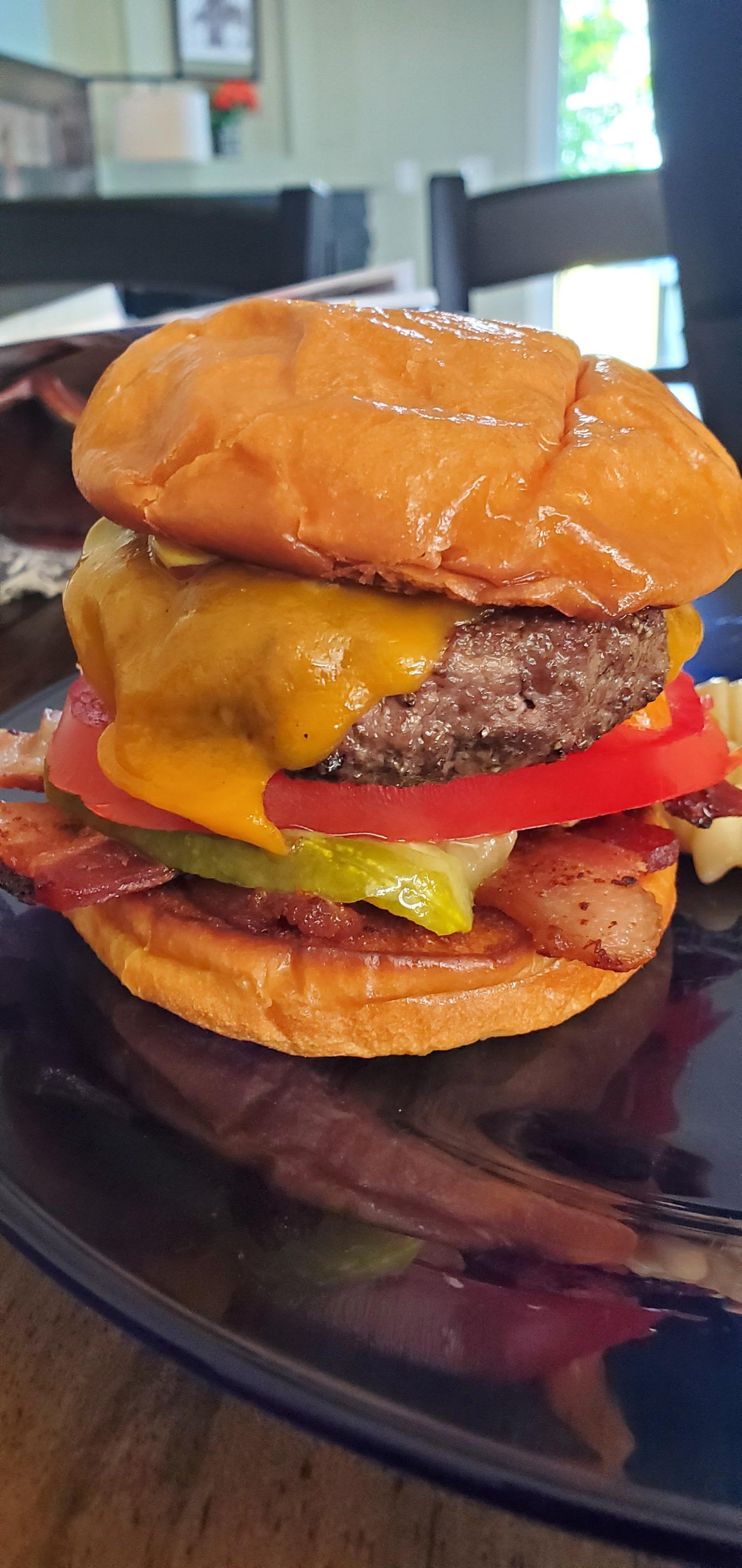 Homemade on toasted brioche bun with bacon cheddar, pickle and tomato