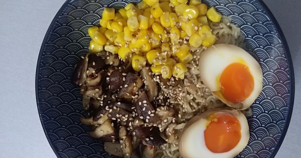 Instant ramen noodles with sweet corn, sesame seeds, shiitake mushrooms and ramen egg.
