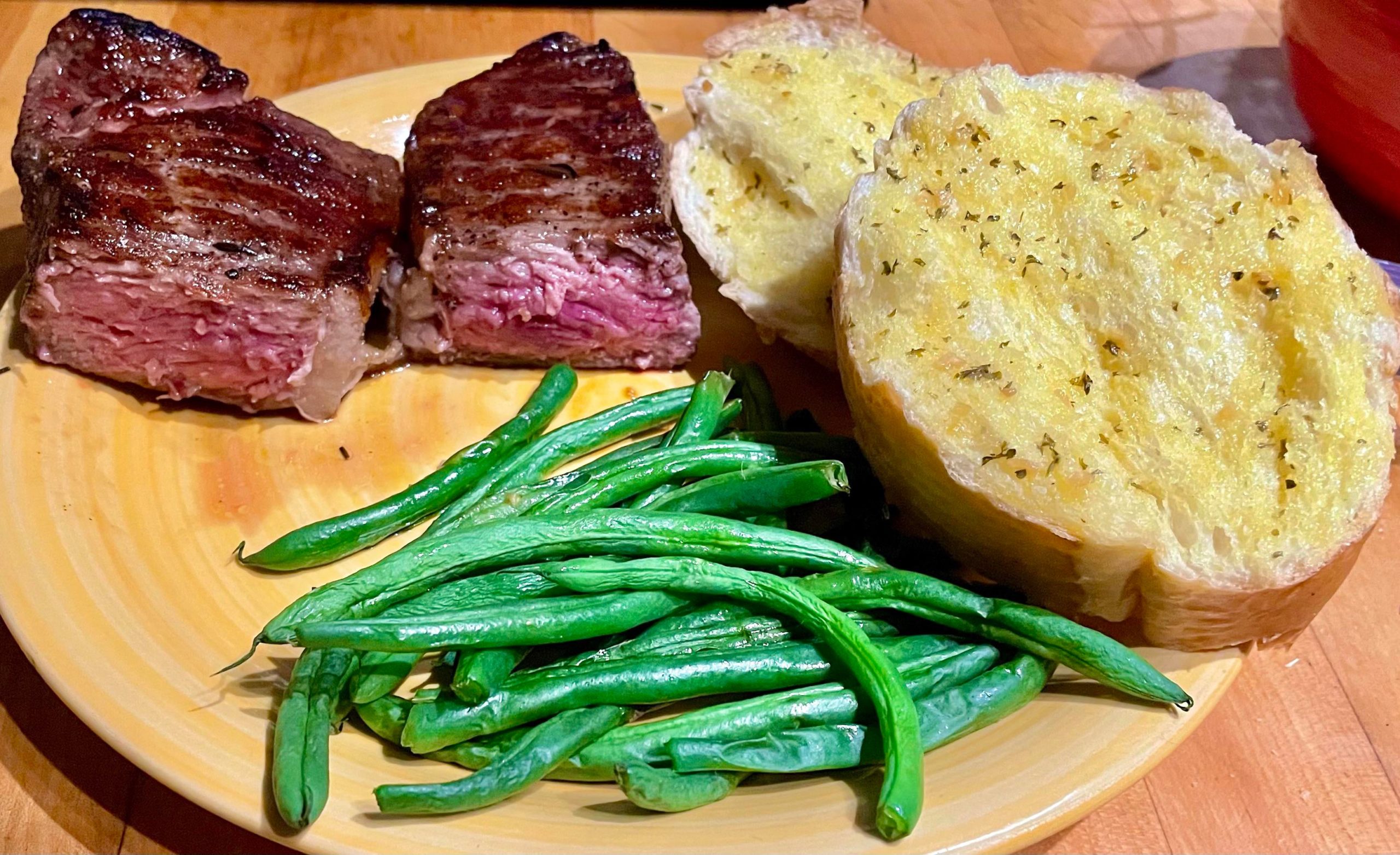 Prime New York Strip with green beans and garlic bread Dining and Cooking