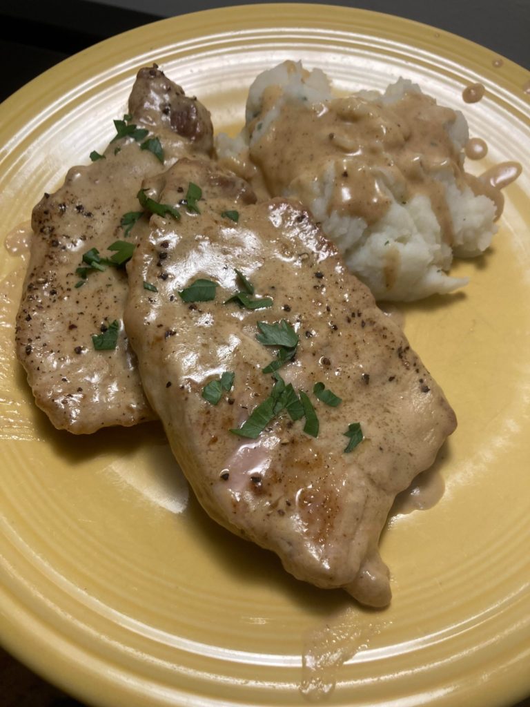 Smothered pork chops with a side of mashed potatoes.