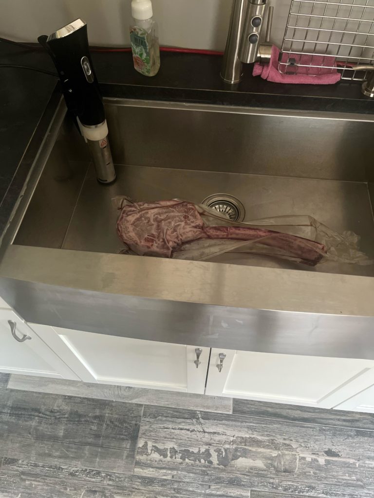 Tomahawk steak (frozen) in a stainless steel sink. Time/temp? 3.5 Lb. 3 inch thick.