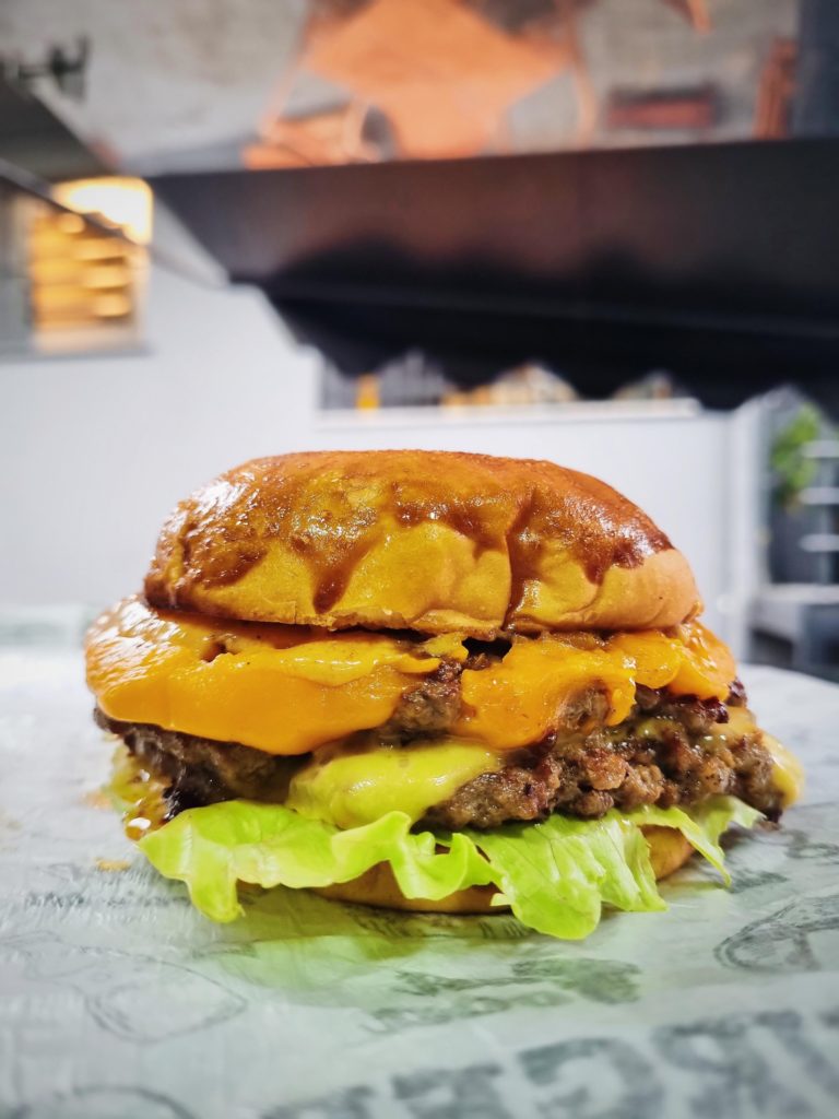 double smash in brioche bun with lettuce and pickled cucumbers