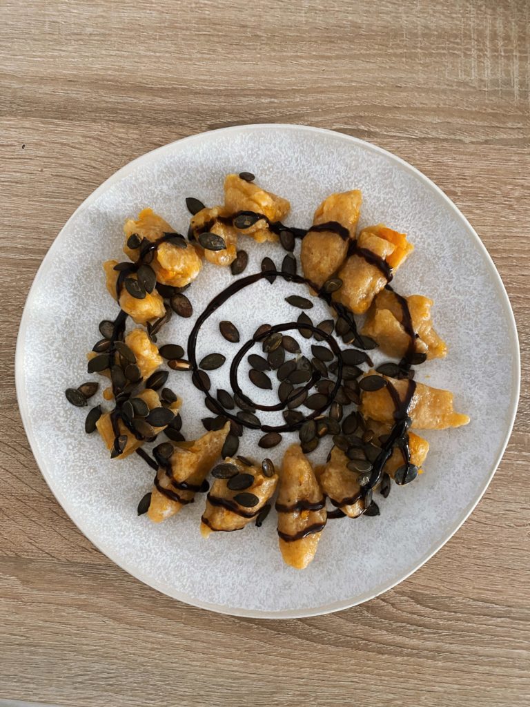 Potato dumplings (kopytka) with a baked pumpkin, served with balsamic vinegar and roasted pumpkin seeds