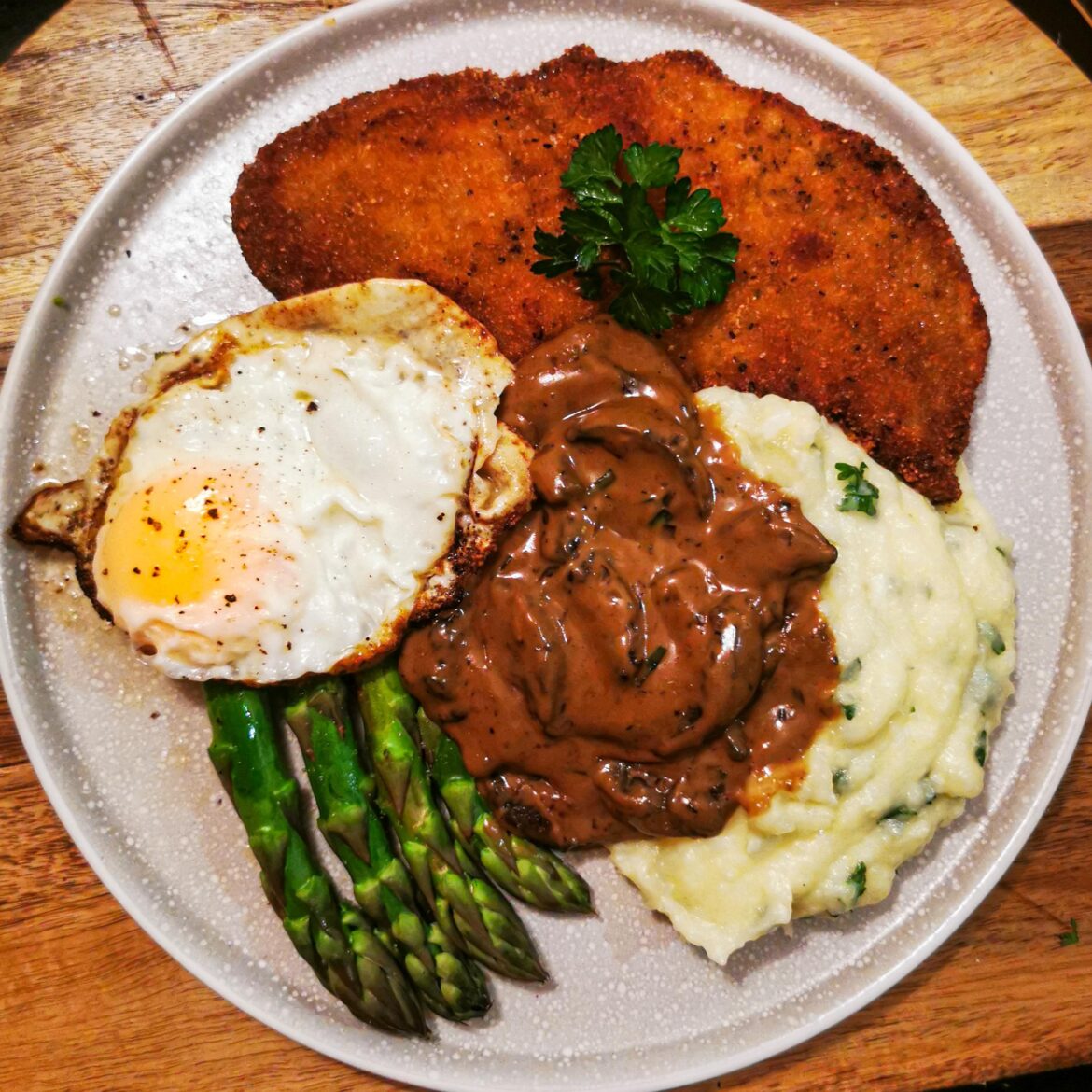 Schnitzel with mashed potatoes, steamed asparagus, fried egg, and mushroom sauce. Made in the style my German husband grew up with, to the best of my ability, in Australia.