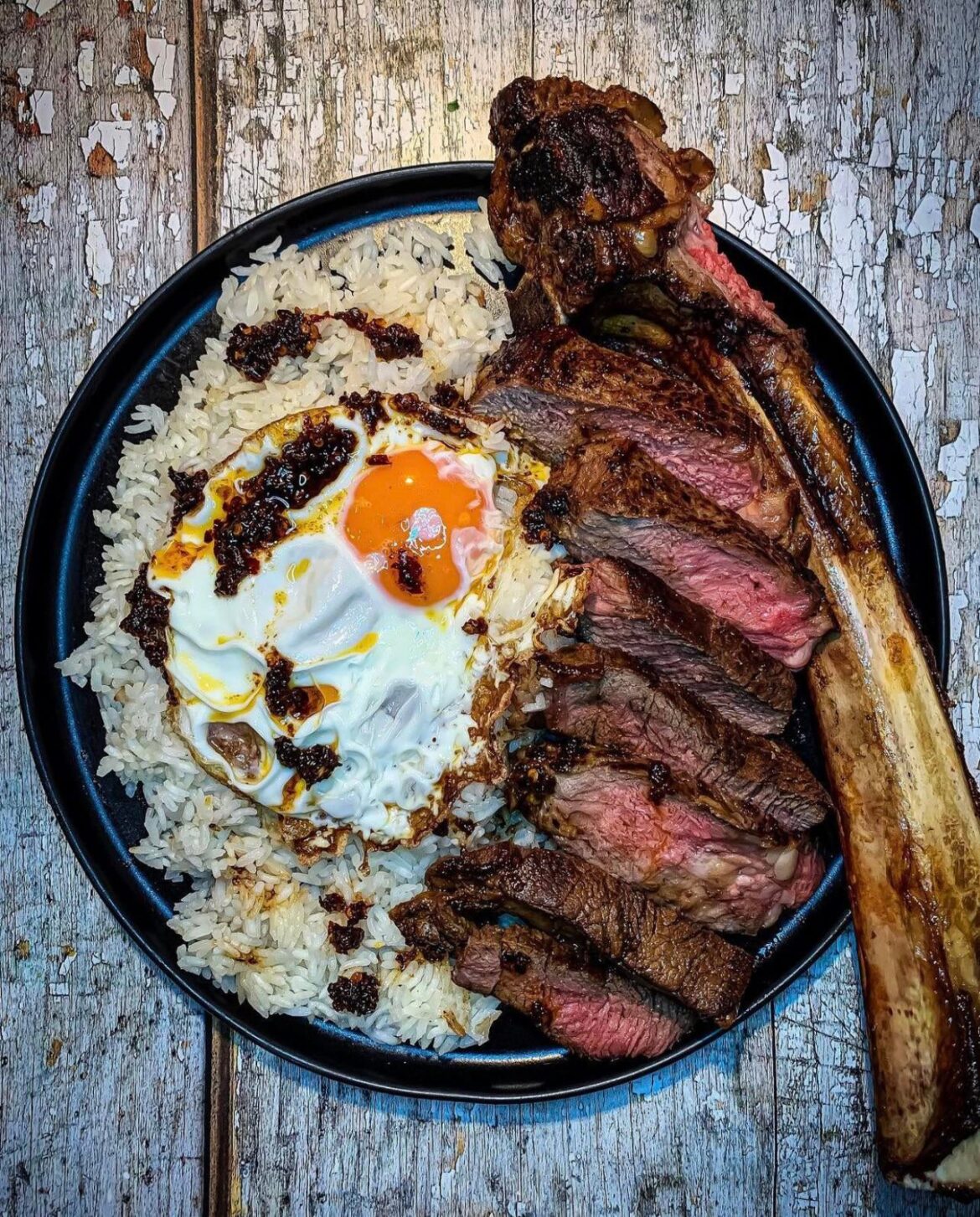 Tomahawk steak, rice, & egg with a dash of chilli oil. Breakfast.