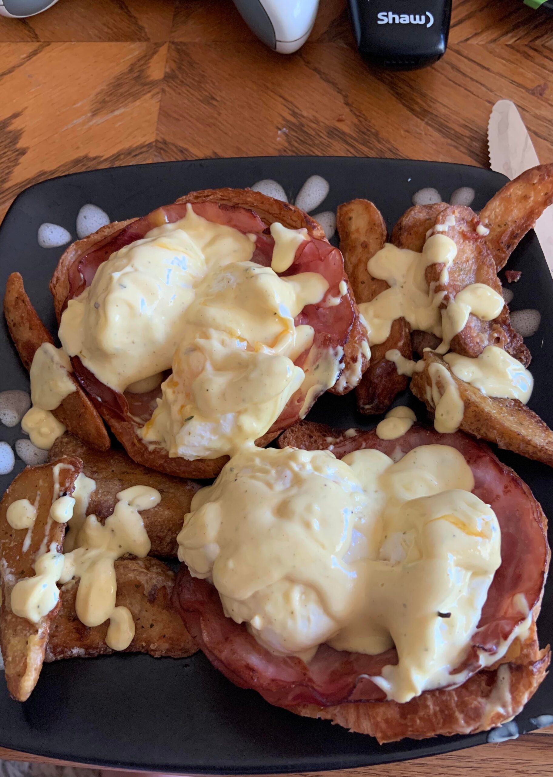 Egg Benny on toasted croissant with rosemary ham and crispy herb potato