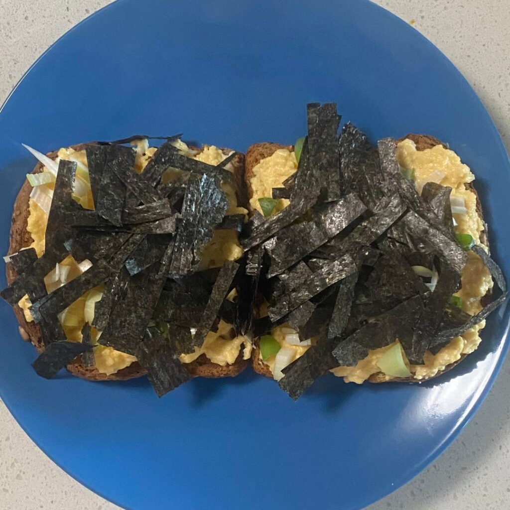 Two eggs, mixed with one tablespoon Mexican sour cream, scrambled in a small pan with half a tbsp canola oil, on two toasted pieces of Dave's Killer Bread, topped with green onion and teriyaki seaweed