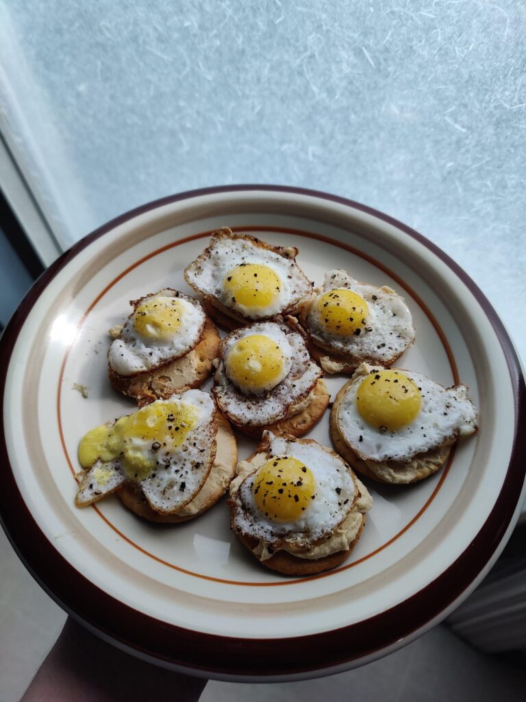 Fried quail eggs on crackers and hummus