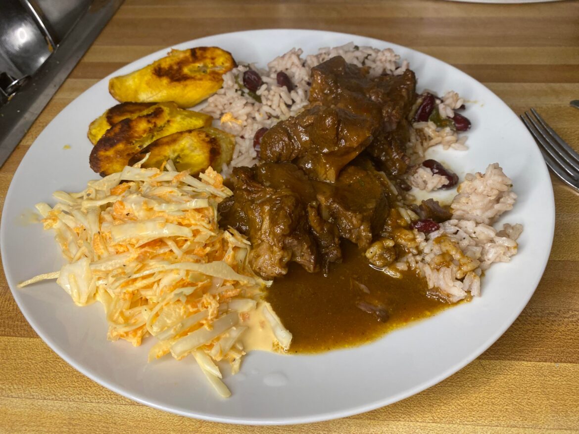 Homemade Jamaican oxtail with rice and peas, fried plantain, and coleslaw