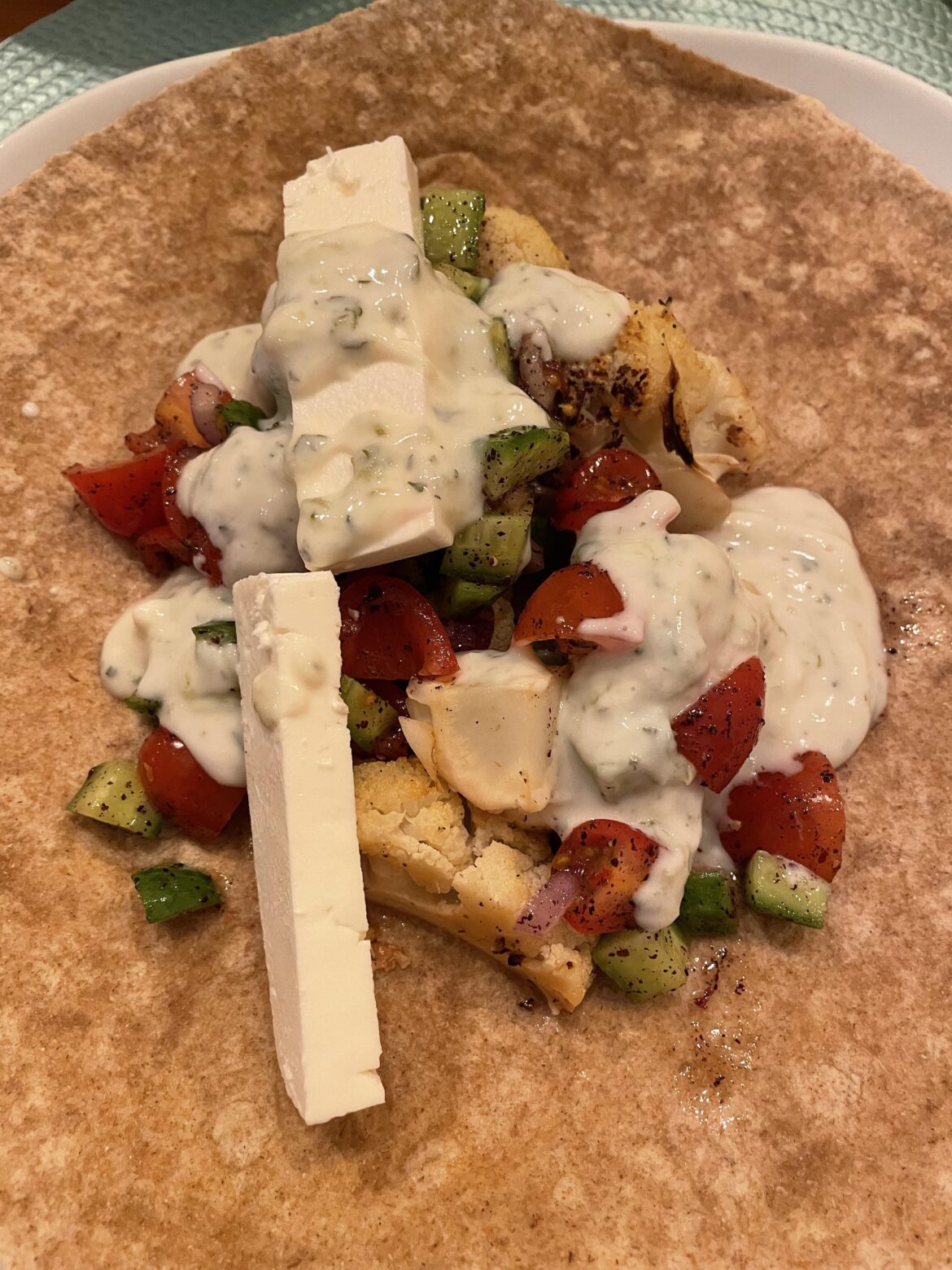 Wrap filled with oven baked cauliflower, salad, yoghurt and feta cheese