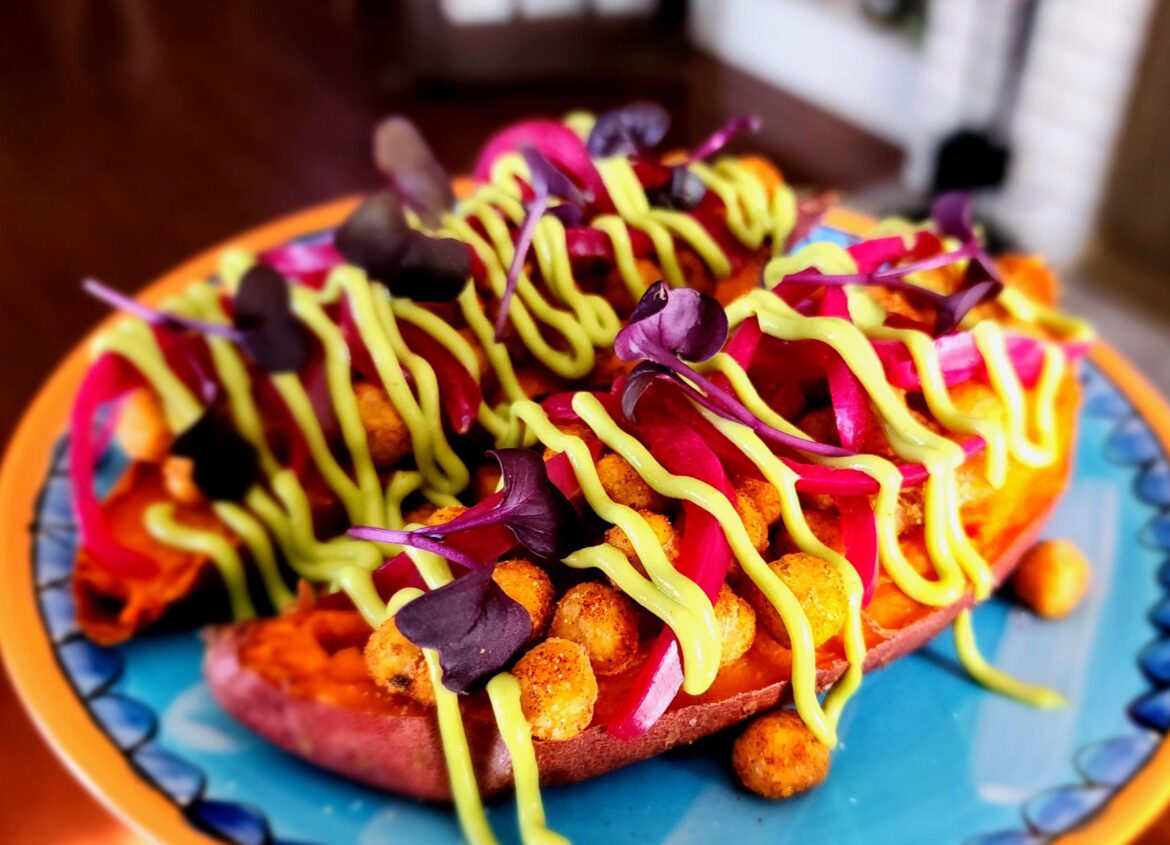 Baked sweet potatoes with spiced crispy chickpeas, pickled onions, radish microgreens, and avocado aioli.