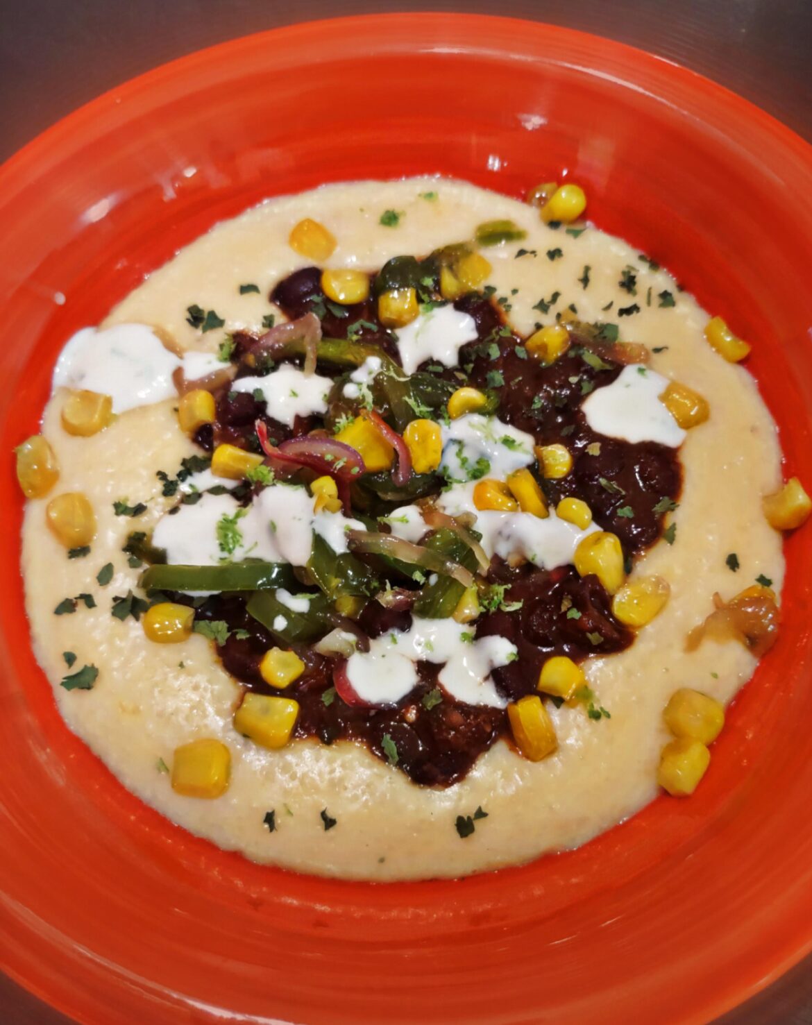 Cheese grits topped with smokey black beans, honey sweet corn and pepper succotash and a lime crema drizzle garnished with lime zest and cilantro.
