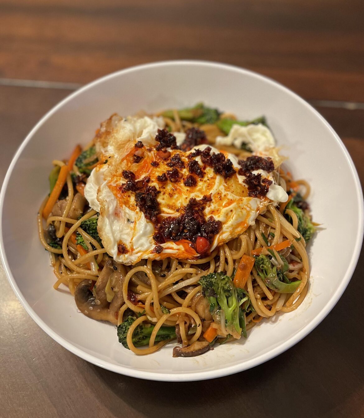Stir-fried noodles with mushrooms, broccoli, carrots, sweet soy sauce and extra crispy fried egg
