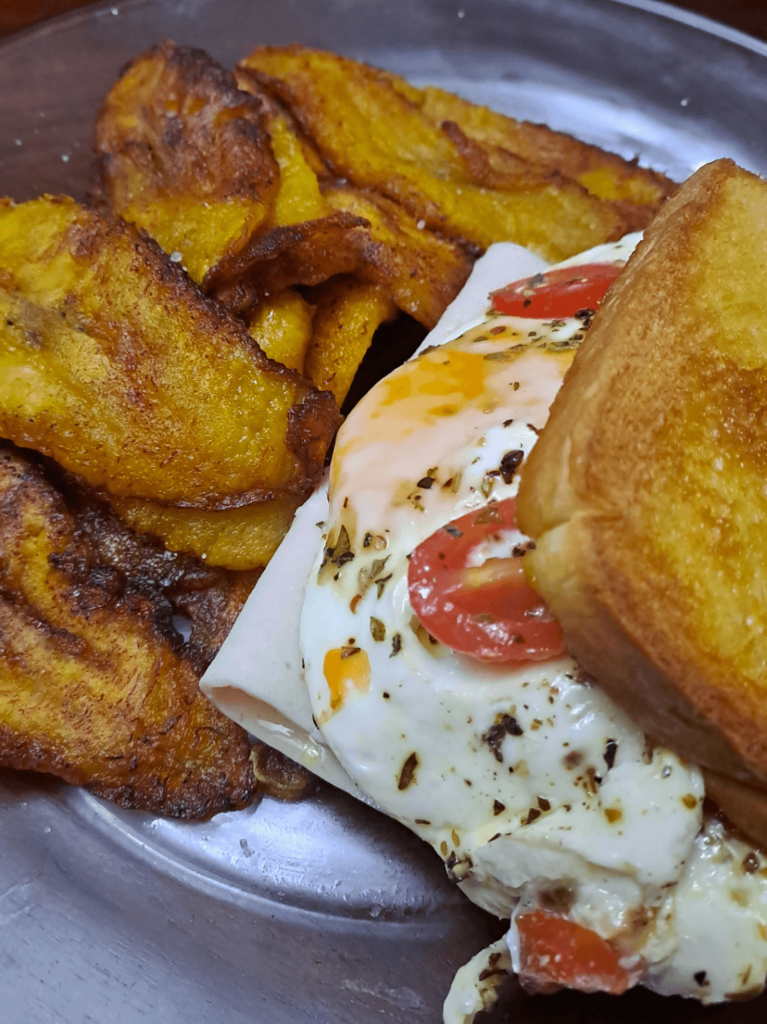 Dinner for my bf: Ripe plantain fritters and ham sandwich with eggs, tomatoes and picante chombo on it.
