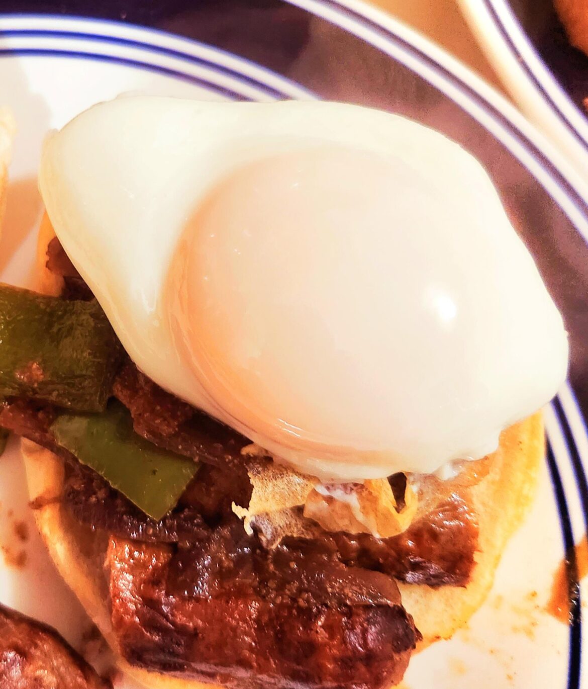 Basted egg on a green bell pepper, mushroom, onion and garlic hash